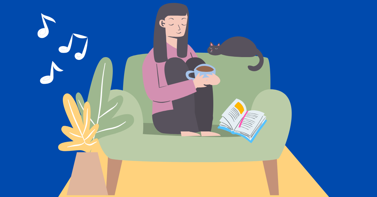 Lady sitting on couch with cat listening to music and reading a book, smiling.